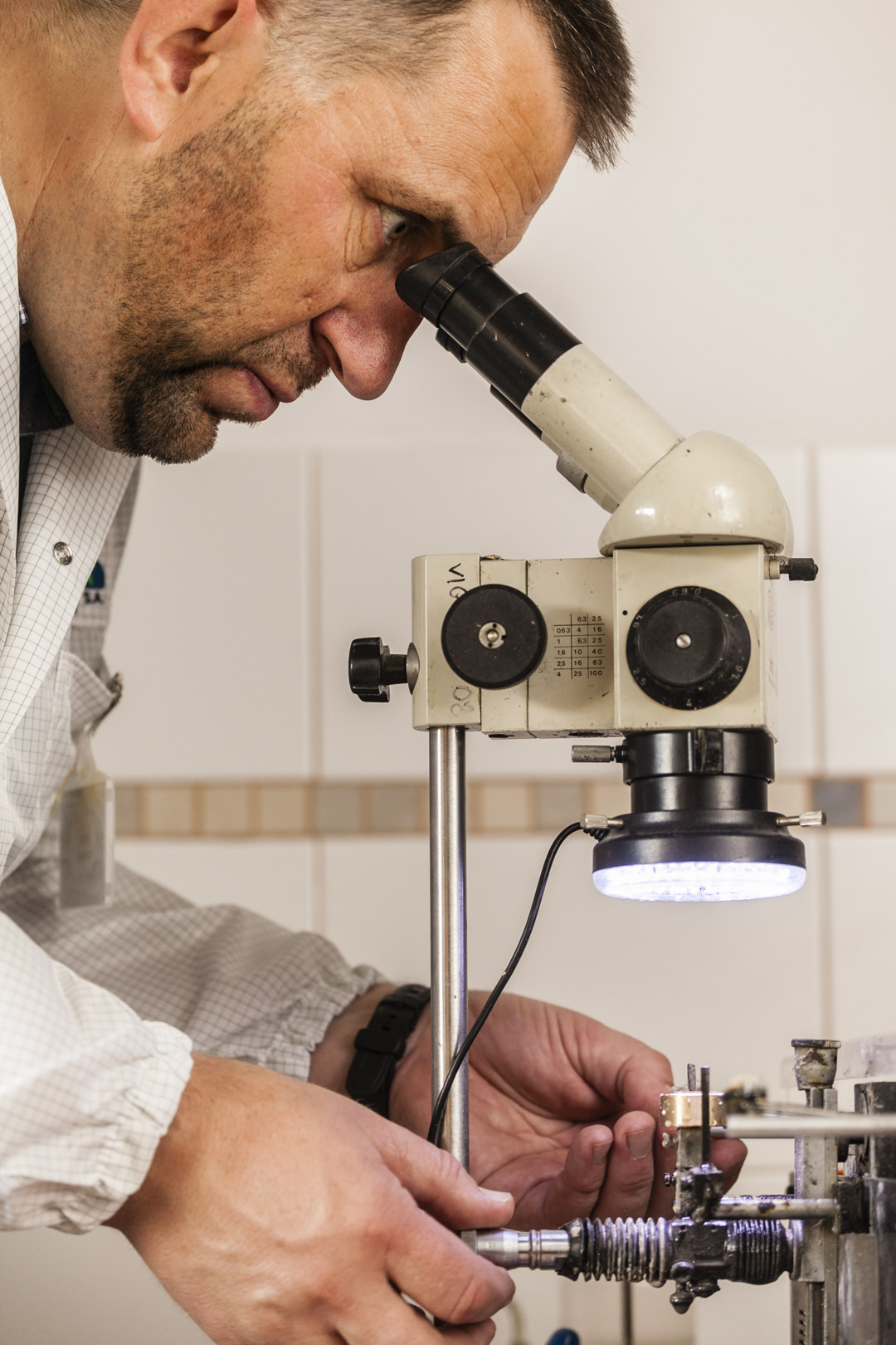 mężczyzna z brodą w średnim wieku patrzy przez mikroskop