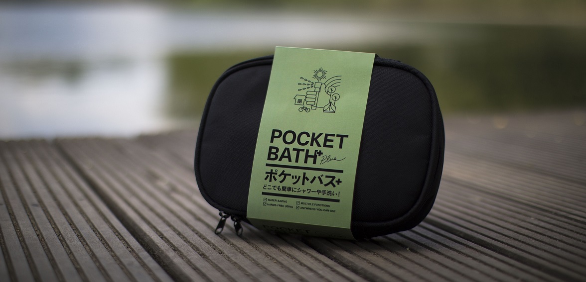 widok na czarną torbę niewielkich rozmiarów z etykietą w oliwkowym kolorze z czarnym napisem Pocket Bath oraz znakami alfabetu japońskiego